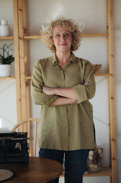 Blonde middle-aged woman with curly hair standind and looking at