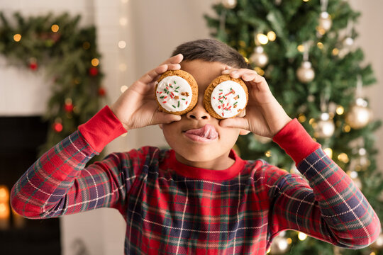 Boy covering eyes with christmas cookies and making a face