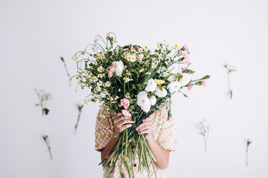 The boy hides behind a large bouquet of flowers