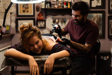 Tattoo artist doing Japanese traditional tattoo on woman's back