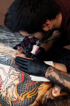 Close up hands of an artist tattooing customer's back. Irezumi tattoo