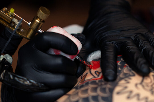 Close up hands of an artist tattooing customer's back. Irezumi tattoo