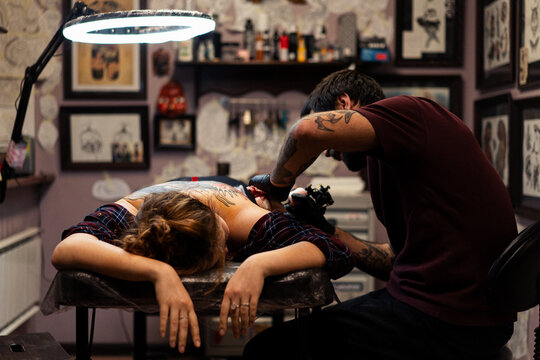 Tattoo artist doing Japanese traditional tattoo on woman's back