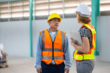 Senior asian man and caucasian engineering team worker people, Success teamwork. Two professional engineering people wearing hardhat safety helmet meeting discussion at warehouse factory