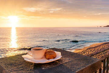 concept of street outdoor breakfast with a cup of tea or coffee on a morning coast during sunrise. landscape of city embarkment with sea water and cloudy sky on background