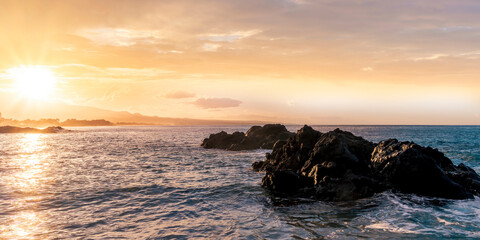 beautiful coast beach with sea gulf water during sunset or sunrise with golden sand, nice black rocks and stones, colorful vawes and clouds in thr sky