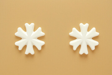 Two white snowflake decorations on golden background. Concept of minimal winter elegance.
