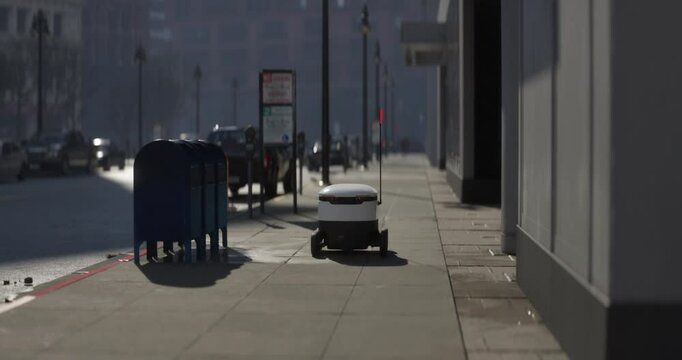 An autonomous delivery robot navigates a city sidewalk. Equipped with a flagpole for visibility, it moves efficiently past parked cars and urban infrastructure, showcasing modern mobility solutions