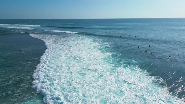Surfers At Uluwatu Beach Enjoying The Waves By Surfing In Bali, Indonesia. aerial shot