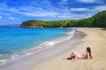 Young woman with a baby girl sitting at Anse La Roche Beach, Carriacou Island, Grenada.
