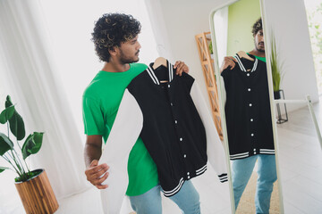 Photo of nice young man hold jacket look mirror wear t-shirt weekend green interior apartment...