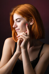 Cute red-haired girl, studio portrait on a black background.