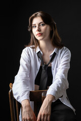 A young girl in a white shirt and black tie in the studio.