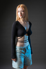 Portrait of a blonde woman with freckles in a sexy top and denim shorts in a studio.