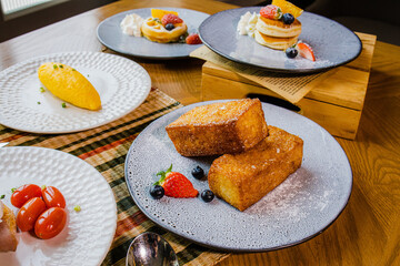 A beautifully arranged dessert spread featuring pancakes, fruits, and a delightful pastry on elegant plates.