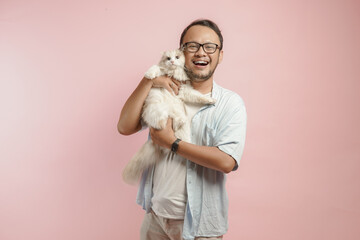 Lovely young Asian man holding a white ragdoll cat and smiling to the camera.