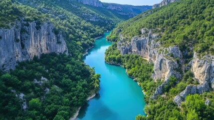 Fototapeta premium Majestic aerial view of a turquoise river snaking through a lush forest with rocky outcrops visible along its banks