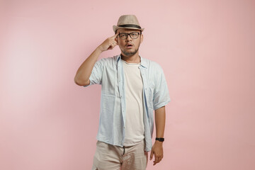 Thoughtful young Asian man wearing blue shirt and hat thinking of an idea with serious expression.