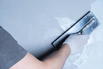 Using a trowel, a person applies epoxy adhesive to repair a wall surface effectively.
