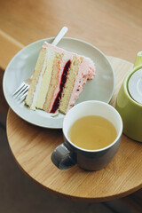 A piece of strawberry cake and tea on a wooden table in a cafe, close-up.