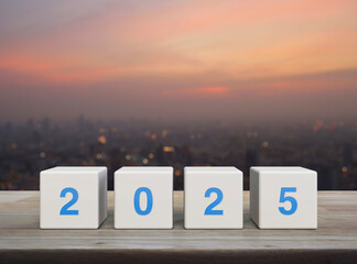 2025 letter on white block cubes on wooden table over blur of cityscape on warm light sundown, Happy new year 2025 cover concept