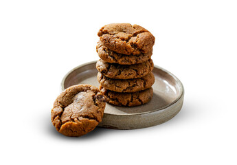 A stack of freshly baked chocolate chip cookies on a rustic ceramic plate, showcasing their golden-brown, chewy texture. One cookie lies invitingly at the base, adding a touch of charm.