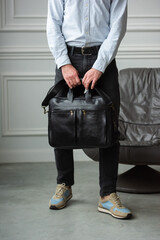 A Stylish and Professional Man Standing with a suitcase. Wearing blue shirt and black jeans