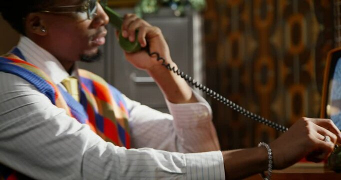 A man is calling on an old phone. He dials a number and starts a conversation. Retro office