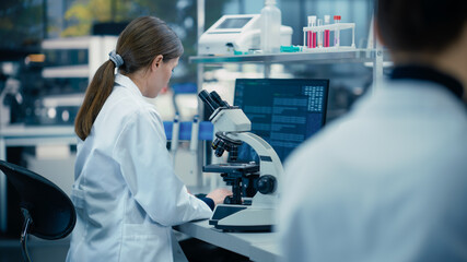 Medical Research Scientist Looking at Biological Samples Under a Microscope in an Applied Science...