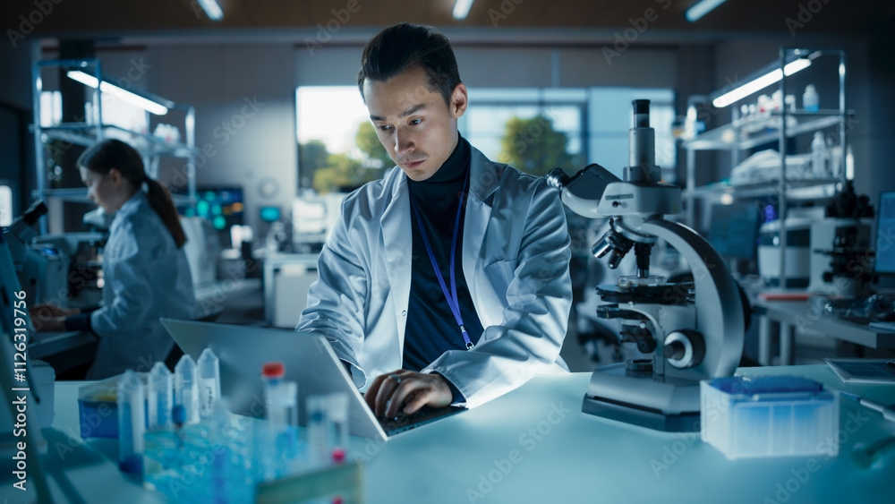 Poster Portrait of a Young Graduate Student Working in a Laboratory, Using Laptop, Writing Down Research Data on a Computer. Multiethnic Biotechnology Specialist Using Modern Tools
