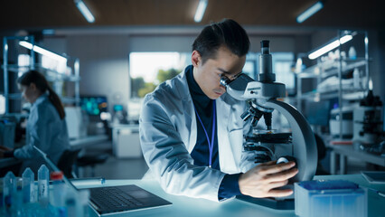 Medical Research Laboratory: Portrait of a Handsome Scientist Using Microscope to Analyze Samples. Advanced Scientific Lab for Medicine, Biotechnology, Microbiology Development