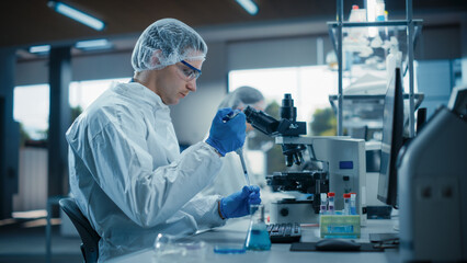 Medical Scientist Wearing Coveralls and Protective Accessories, Using Micro Pipette while Working with Biological Samples. Sterile Vaccine and Drugs Research and Development in Innovative Laboratory