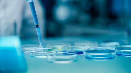 Close Up of a Scientist Pouring Clear Liquid into Glass Dishes with a Micro Pipette, Conducting Scientific Experiment in Laboratory Setting. Chemistry Concept for Medical Research and Analysis