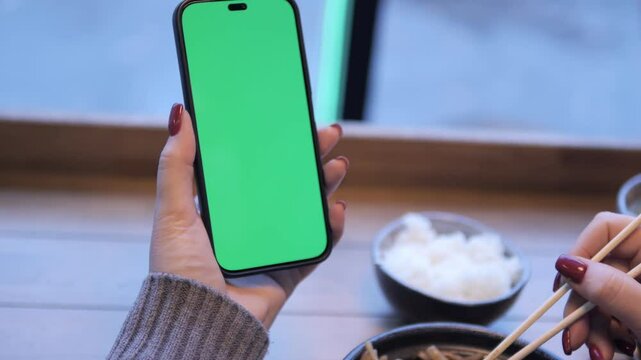 A smartphone featuring a vibrant green screen placed in a modern restaurant environment