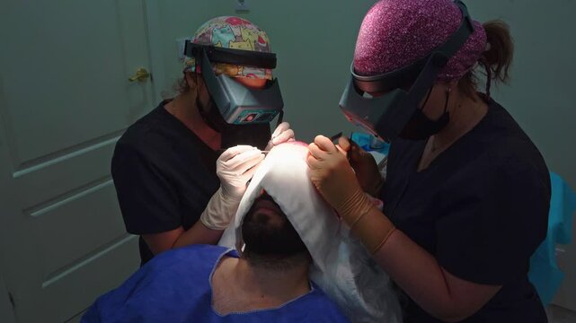 Surgeons performing detailed hair transplant procedure on patient