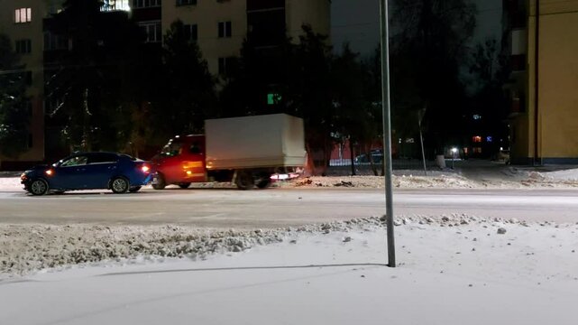 Road traffic accident in winter on a slippery road in the city with cars with hazard warning lights. Copy space for text, evening
