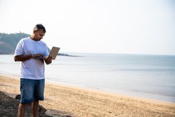 Man working with laptop on beach.