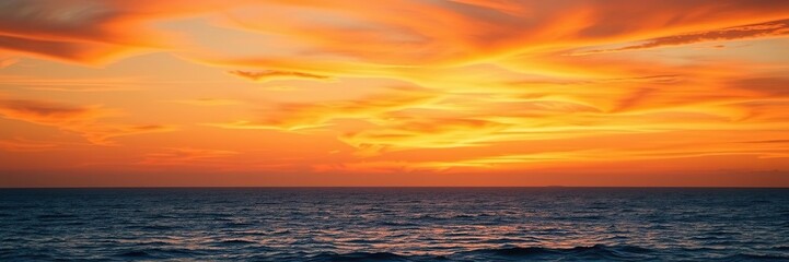 Fototapeta premium Vibrant orange hues with gentle wisps of cloud, softly fading into the serene blue ocean at dusk, calmness, color