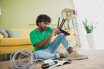 Full size photo of nice young man connect cable wifi router wear t-shirt modern green interior...