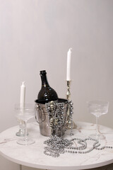 Table with white candles and a bottle of champagne. On a white background. Decor. Christmas. Close-up. Copyspace