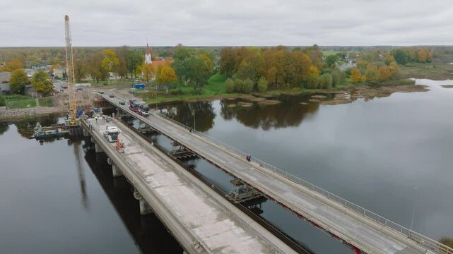 Aerial panoramic establishing view of Salacgriva city Salaca river bridge construction site, European countryside, cars crossing