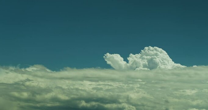 Timelapse of dynamic fluffy white and grey clouds gathering for a storm and billowing and swelling in the clear blue sky