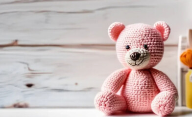 Pink crochet teddy bear on wooden background.