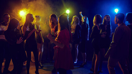 Group of young cheerful people, men and women, friends, students celebrating Christmas, attending...
