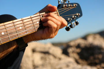 Close-up of a man playing the E chord on an acoustic guitar