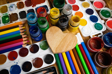 Wooden heart in the middle of watercolor, gouache, colored pencils, crayons