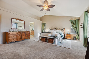 Spacious modern bedroom featuring a cozy seating area and stylish decor in a serene environment with natural light