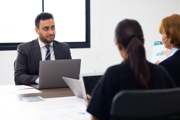 Male sitting on desk with laptop computer. Portrait of Confident successful business people woking in office. rich confident business man owner in office.