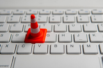 A miniature traffic cone placed on a computer keyboard. Website maintenance, technical...