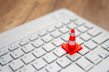 A miniature traffic cone placed on a computer keyboard. Website maintenance, technical...
